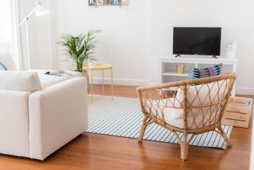 a living room with a chair and a tv at Apartamentos Praça Amarela by Heart of Funchal in Funchal