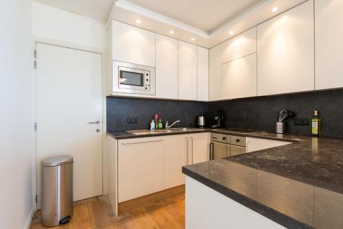 a kitchen with white cabinets and a black counter top at Seaview Zeebrugge in Zeebrugge