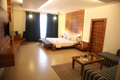 una camera d'albergo con letto e divano di Hotel Kanha’s Palm Springs a Bhopal