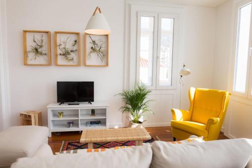 a living room with a couch and a yellow chair at Apartamentos Praça Amarela by Heart of Funchal in Funchal