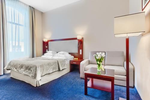 a bedroom with a bed and a couch and a chair at Hotel Atrium in Szczecin