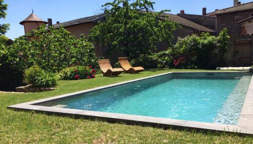 einen Pool in einem Garten mit zwei Bänken in der Unterkunft Manoir au sein du village in Saint-Haon-le-Châtel