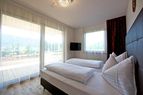 Schlafzimmer mit einem Bett und einem großen Fenster in der Unterkunft Apart Hotel Legendär in Steindorf am Ossiacher See