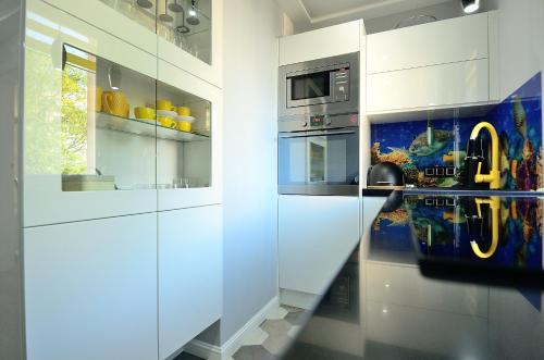 ソポトにあるVictus Apartamenty, Apartament Teslaのキッチン(白いキャビネット、カウンタートップ付)