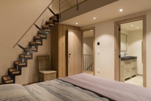 a bedroom with a bed and a staircase at B&B De Windheer in Sint-Martens-Lennik