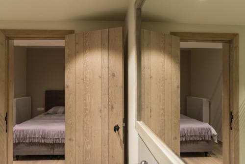 a bedroom with two beds and a door with a mirror at B&B De Windheer in Sint-Martens-Lennik