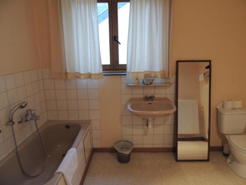 a bathroom with a tub and a sink and a toilet at Hotel Beau Rivage and Restaurant Koulic in La Roche-en-Ardenne