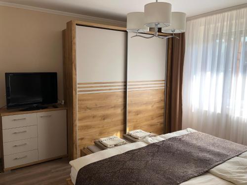 a bedroom with a bed and a flat screen tv at Leiner Apartman in Hévíz