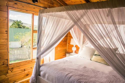 a bedroom with a canopy bed with a window at Anna Beulah Farm in Durbanville