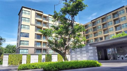 an apartment building with a tree in front of it at The Rain Cha Am by Paka in Cha Am