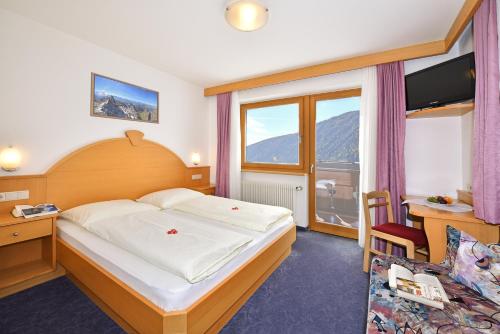 Schlafzimmer mit einem Bett, einem Schreibtisch und einem Fenster in der Unterkunft Pension Tasa in Vals