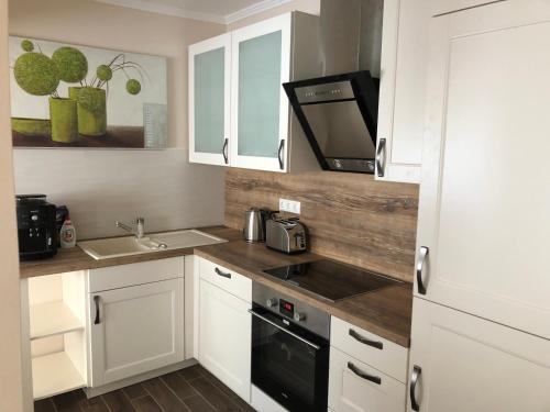 a kitchen with white cabinets and a sink and a microwave at Leiner Apartman in Hévíz