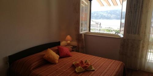 a bedroom with a bed with a window and two flowers on it at Apartments Miro with Sea view - near Beach in Sumartin