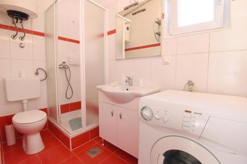 a bathroom with a toilet sink and a washing machine at Sun and sea apartment in Zadar