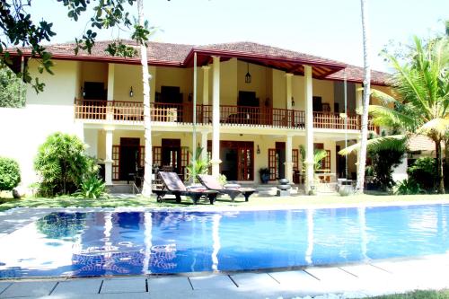 una casa con piscina frente a ella en Good Karma Villa, en Bentota