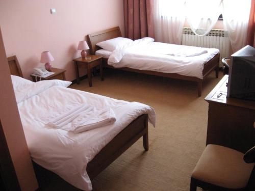 Habitación de hotel con 2 camas con sábanas blancas en Hotel Vila Sunce, en Stara Pazova