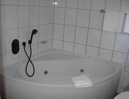 a white bath tub with a shower head in a bathroom at Hotel Daun in Castrop-Rauxel
