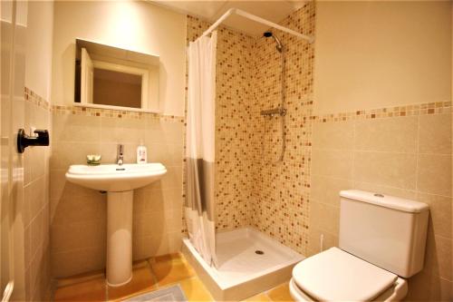 La salle de bains est pourvue de toilettes, d'un lavabo et d'une douche. dans l'établissement Sierra Cortina jardín, sol y playa, à Finestrat