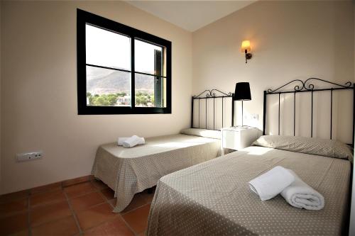 フィネストラットにあるSierra Cortina jardín, sol y playaのベッドルーム1室(ベッド2台、窓付)