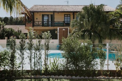 a villa with a swimming pool in front of a house at Pousada Santa Genoveva campeche in Florianópolis
