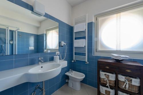 a blue bathroom with a sink and a toilet at Vialeromadodici Rooms & Apartments in Lazise