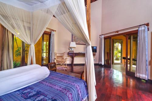 a bedroom with a bed and a desk at Villa Plawa Asri in Seminyak