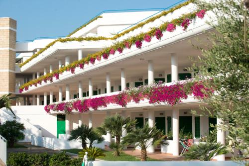 a white building with pink flowers on it at Corvino Resort in Monopoli