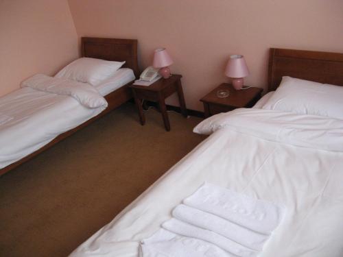 two beds in a room with two lamps and a phone at Hotel Vila Sunce in Stara Pazova
