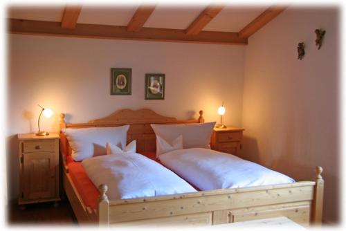 1 dormitorio con 2 camas y almohadas blancas en Ferienapartment Haus Raith en Kreuth