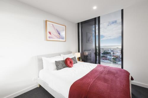 a bedroom with a white bed and a large window at Ascent Apartment with Ocean Views by Ready Set Host in Melbourne