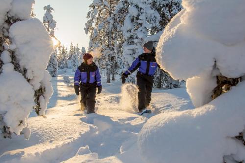 three men walking through the snow on a trail at Ylläs Lake Hotel in Ylläsjärvi