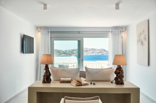 a room with a table with two lamps and a window at Manoula's Beach Mykonos Resort in Agios Ioannis Mykonos