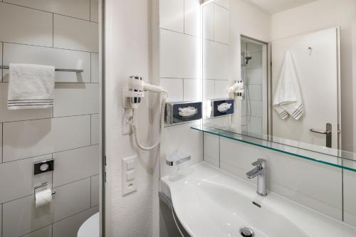 a white bathroom with a sink and a mirror at Hotel Bellinzona Sud Swiss Quality in Monte Carasso