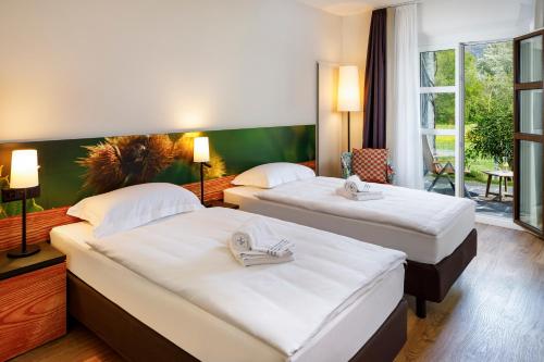 
a hotel room with two beds and two lamps at Hotel Bellinzona Sud Swiss Quality in Monte Carasso
