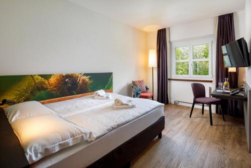 a hotel room with a bed and a desk at Hotel Bellinzona Sud Swiss Quality in Monte Carasso