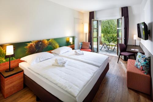a bedroom with a large white bed and a living room at Hotel Bellinzona Sud Swiss Quality in Monte Carasso