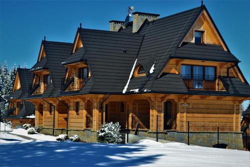a large wooden house with a black roof at Rezydencja NOVA na Gubałówce in Zakopane
