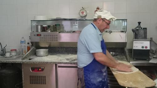 a man in a kitchen making a pizza at Camping Nube D'Argento in Sorrento