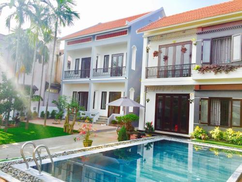 a villa with a swimming pool in front of a building at Yen villa Hội An in Hoi An