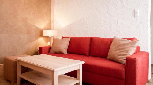 a living room with a red couch and a table at Das Traditionshotel Schwarzer Adler in Tannheim