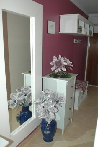 a room with a mirror and a blue vase with flowers at House Villa Mare in Malinska