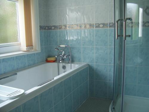 a bathroom with a shower and a tub and a sink at The Tops Self Catering in Leeds