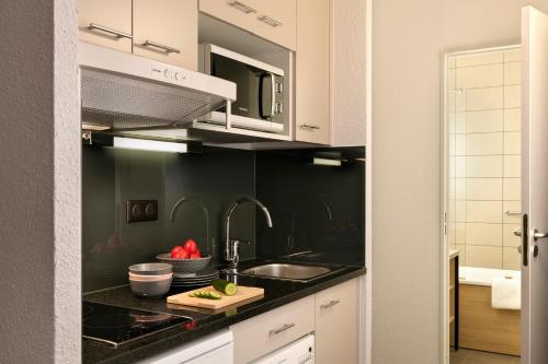 a kitchen with a sink and a counter top at Citadines Kléber Strasbourg in Strasbourg