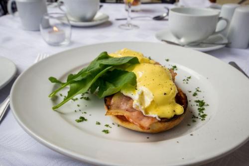 a white plate with an egg sandwich on a table at Lemoenkloof Boutique Hotel in Paarl