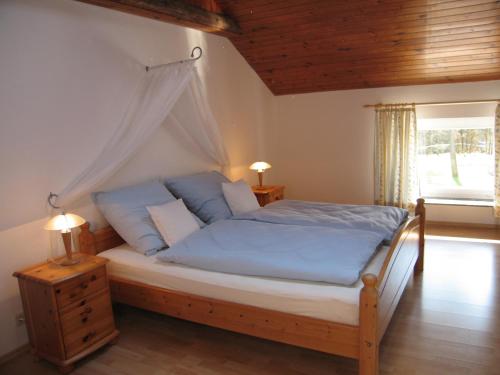 Schlafzimmer mit einem Bett mit blauer Bettwäsche und einem Fenster in der Unterkunft Ferienwohnung Hubner in Bernlohe