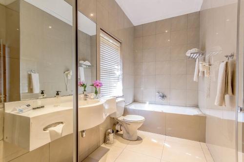 a bathroom with a sink and a toilet and a tub at Lemoenkloof Boutique Hotel in Paarl