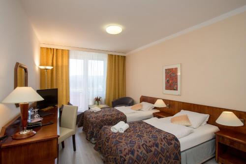 a hotel room with two beds and a desk at Fontána Lipno in Černá v Pošumaví