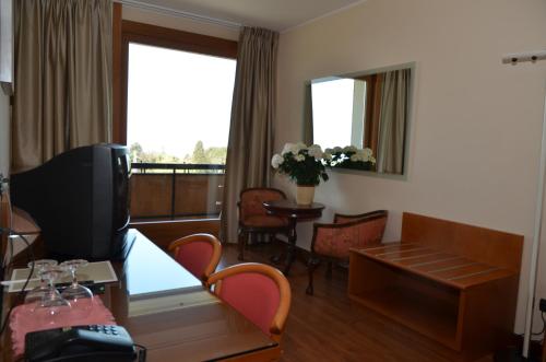 a living room with a television and a table with chairs at Parc Hotel Casa Mia in Lazise
