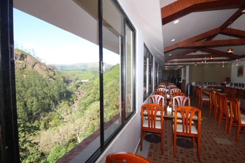 a restaurant with tables and chairs with a view at Abad Copper Castle Resort in Munnar