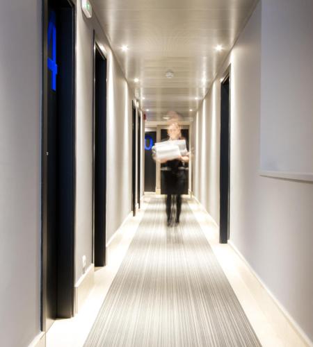 a woman walking down a hallway with a suitcase at Hotel Pamplona Plaza in Pamplona